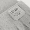 American Vintage Zinaco sjaal ZI20AH26GRICHL in Gris Chiné Noir, lichtgrijze gemêleerde gebreide sjaal met franjes en American Vintage logolabel.