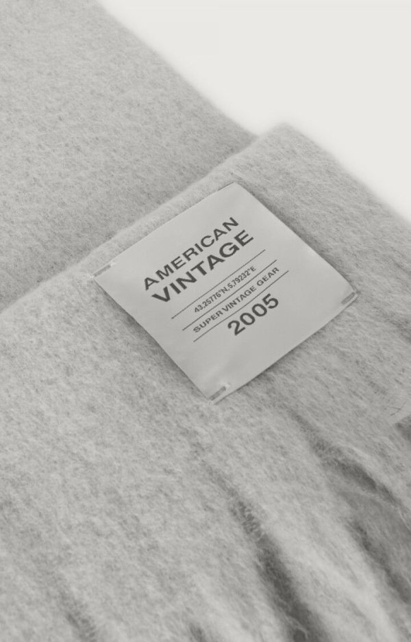 American Vintage Zinaco sjaal ZI20AH26GRICHL in Gris Chiné Noir, lichtgrijze gemêleerde gebreide sjaal met franjes en American Vintage logolabel.